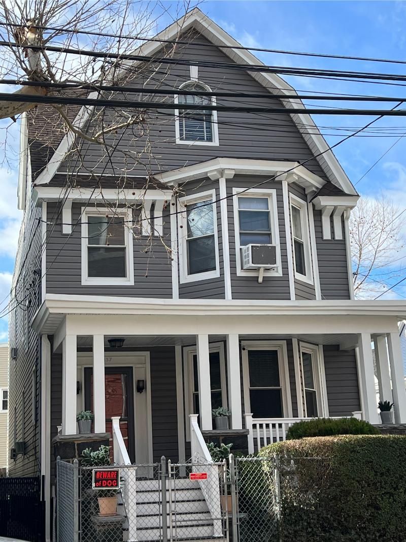 Gray two-story house with white trim, front porch, and small fenced yard