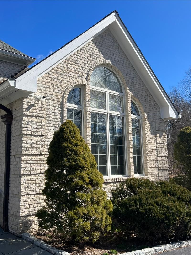 Stone house facade with large arched windows and a gabled roof under a clear blue sky