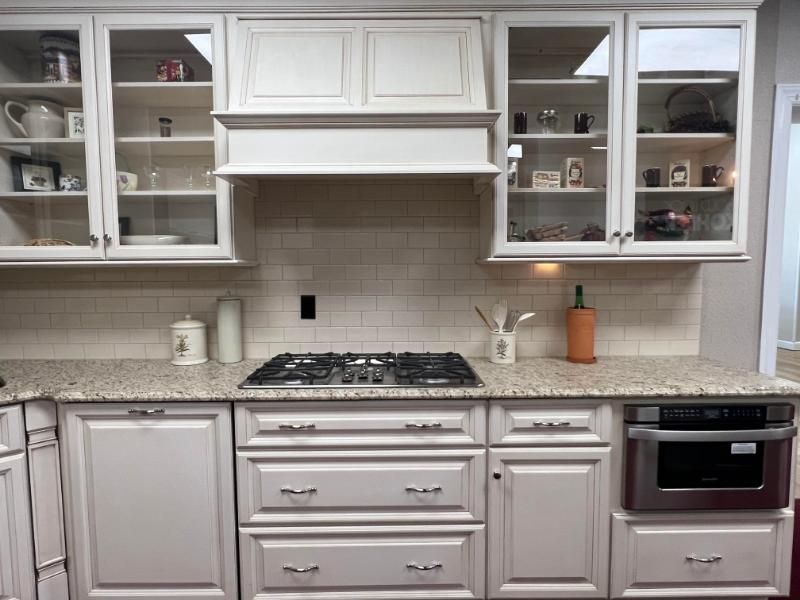 White kitchen with gray cabinets, tile backsplash, gas range, and open glass-front cupboards