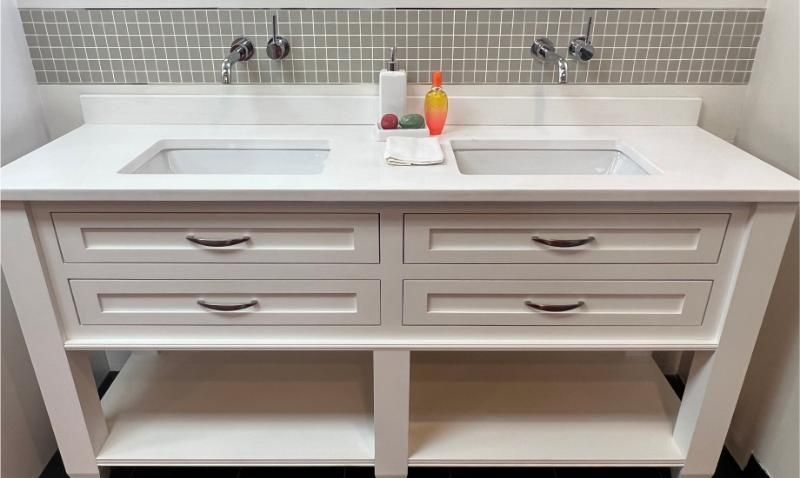 Double-sink white bathroom vanity with gray backsplash and open storage shelves
