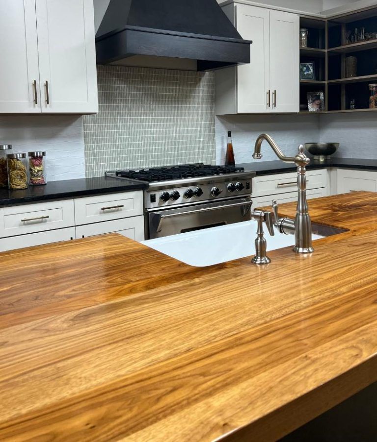 Modern kitchen with white cabinets, stainless range hood, and a large wooden island counter