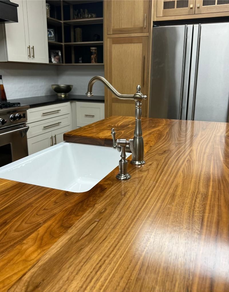 Modern kitchen with a wood countertop, white sink, stainless fridge, and tall faucet