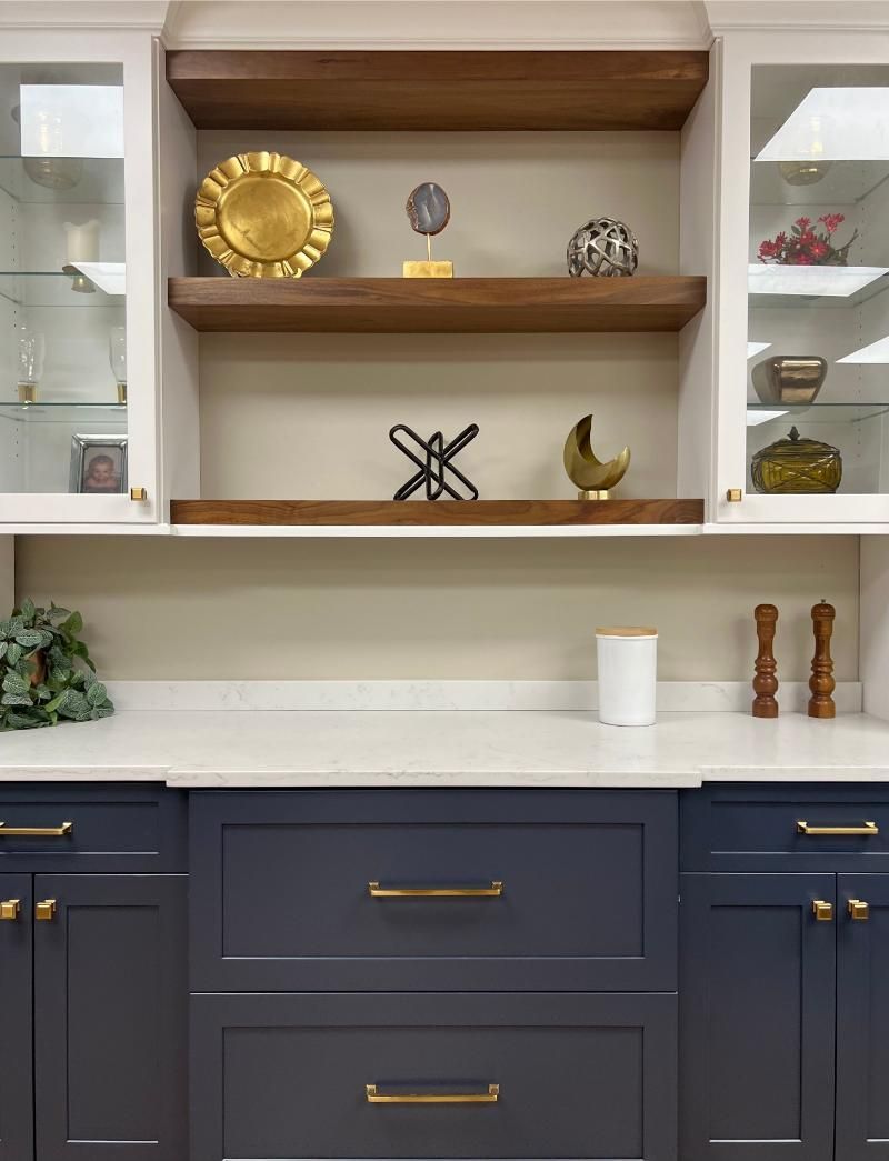 Blue built-in cabinets with open shelves, white backsplash, and gold decor accents in a kitchen nook