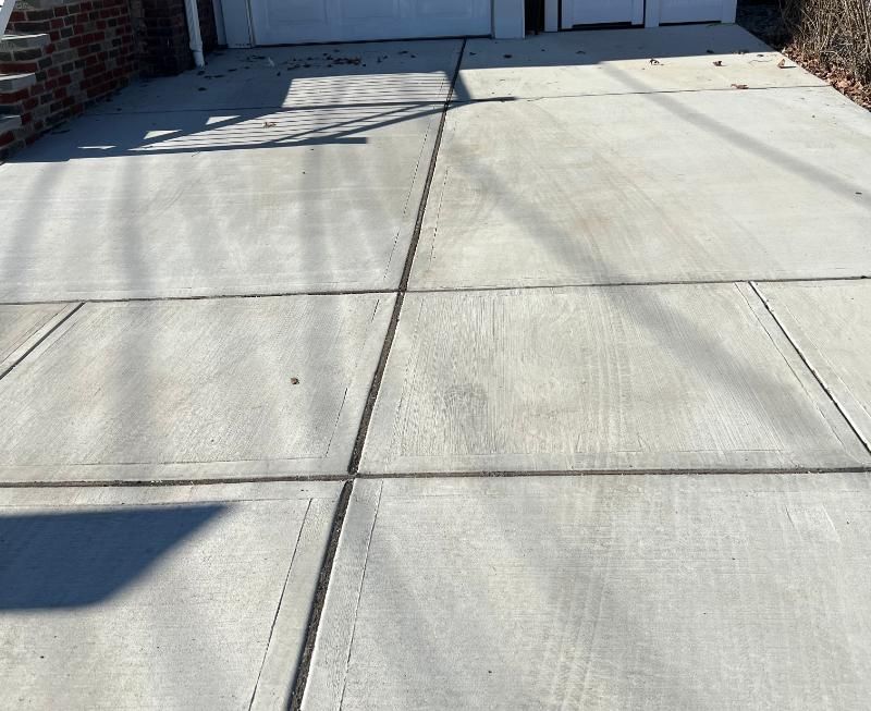 Concrete driveway with expansion joints and shadows near a garage entrance
