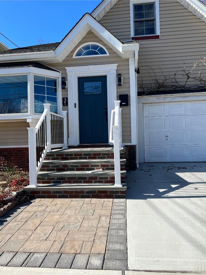 Front entrance of a house with blue door, white trim, steps, and attached garage
