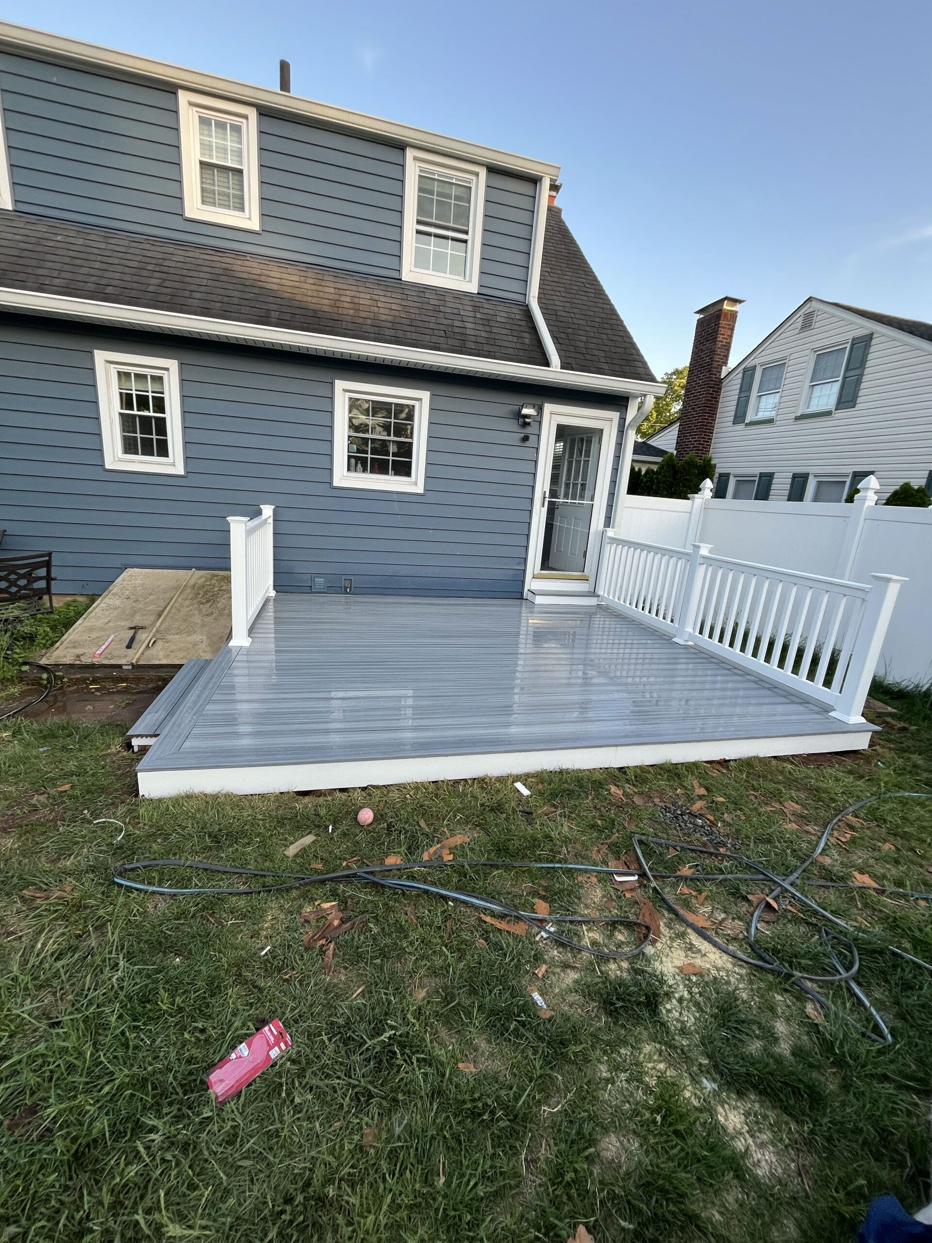 Gray house with a white-fenced wooden deck in a backyard