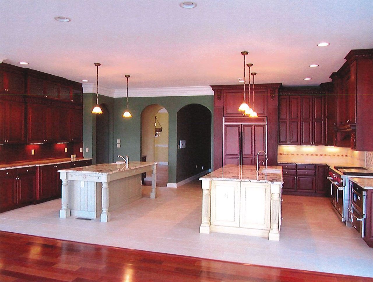 Spacious kitchen with dark wood cabinets, white island counters, and pendant lights under a high ceiling