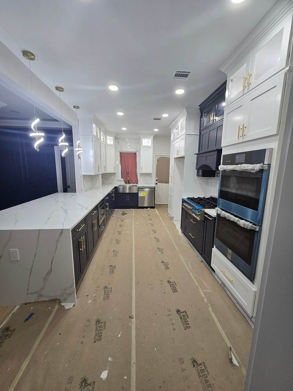 Bright walk-in closet with white cabinets, dark shelving, and a beige carpet runner.