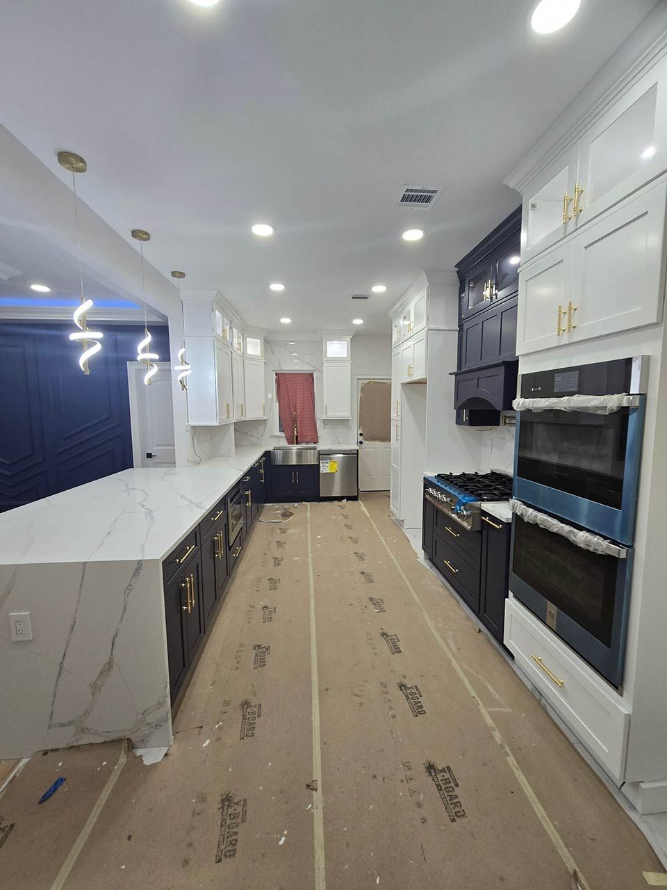 Long, narrow modern kitchen with white cabinets, dark counters, and a beige runner rug