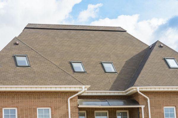 House roof with several skylights under a cloudy sky