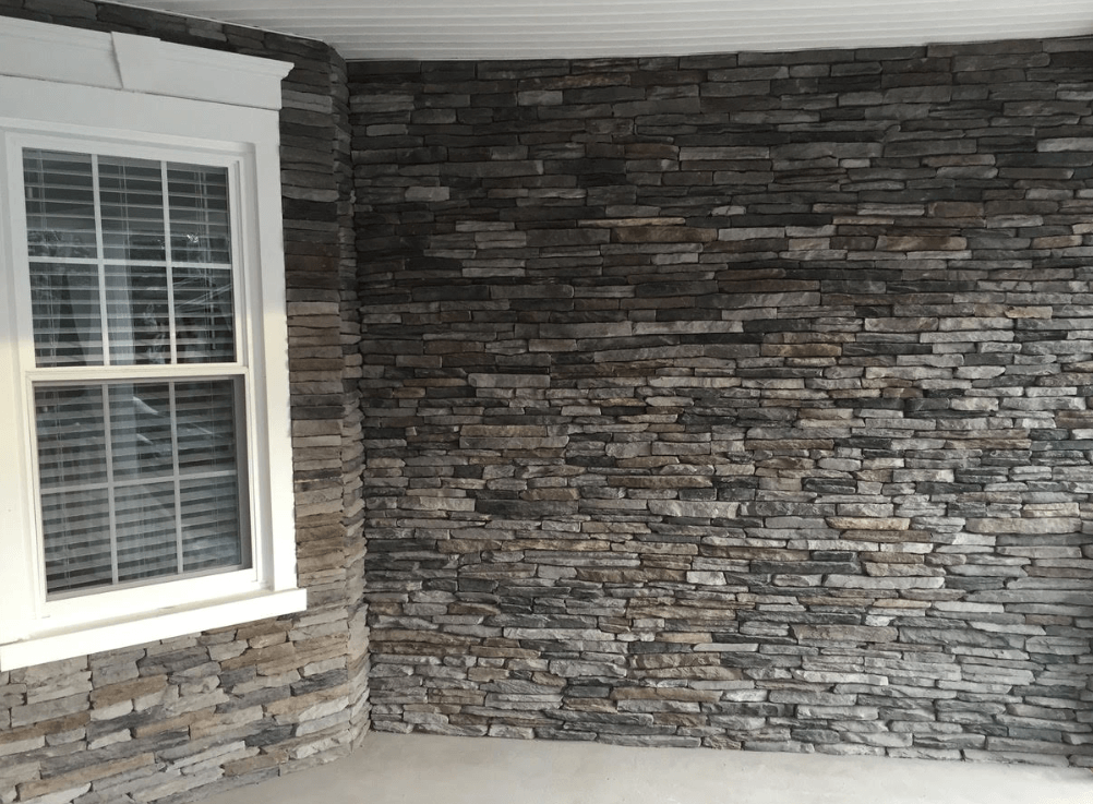 Stone accent wall with a white-trimmed window in an indoor room corner