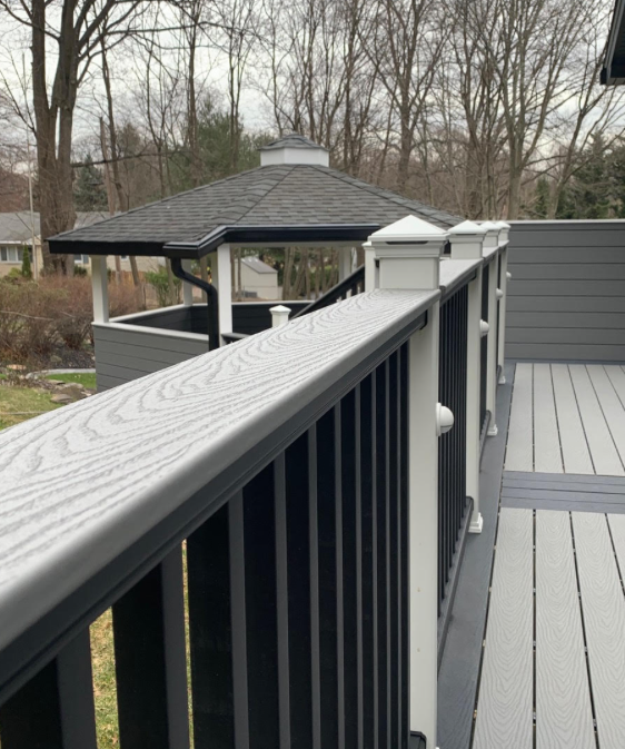 Black deck railing with white top rail overlooking a backyard gazebo and leafless trees.