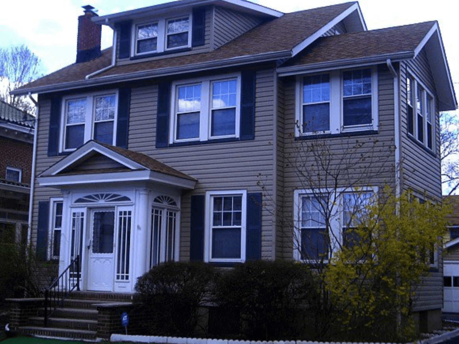 Two-story gray house with white trim, front porch, and gabled roof