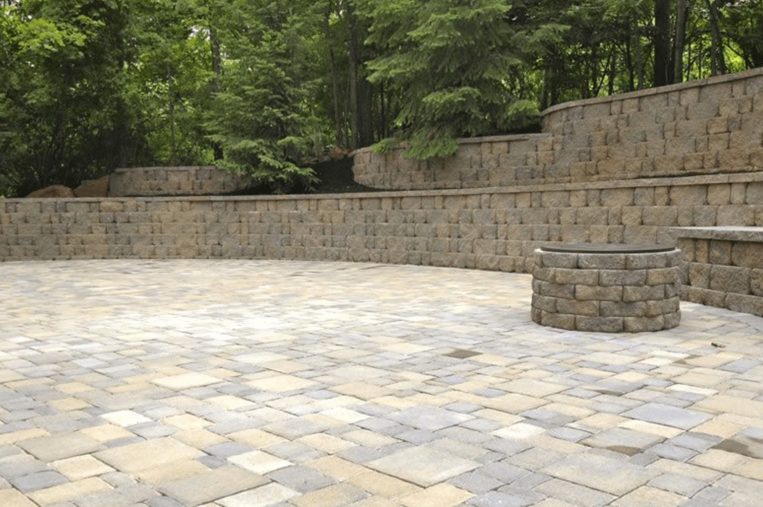 Stone-paved plaza with low retaining walls and trees in the background