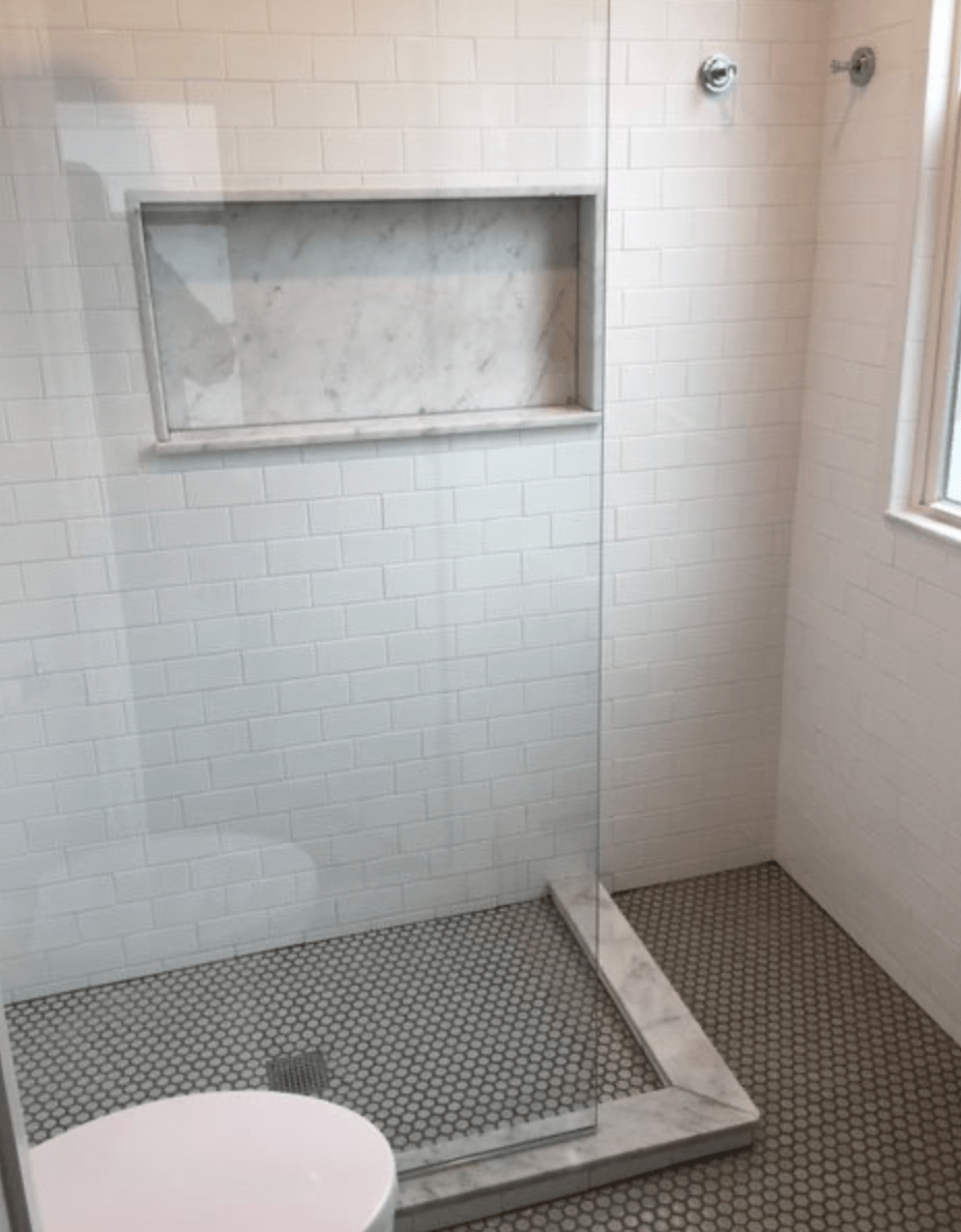 Accessible shower with a fold-down bench, white tiled walls, and a grab bar in a bathroom