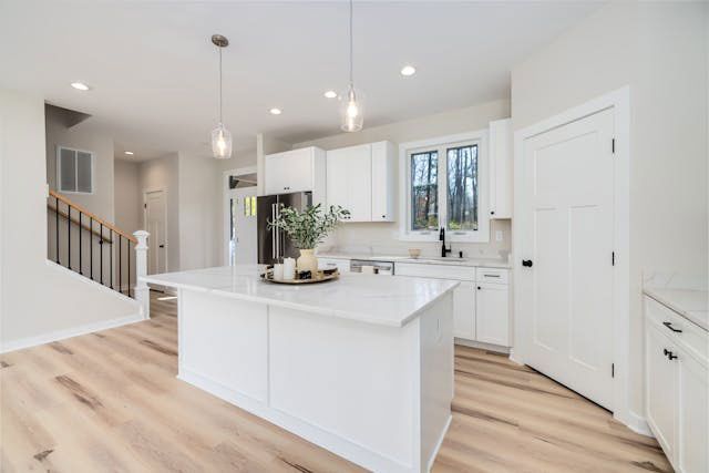 Bright modern kitchen with white cabinets, island, pendant lights, and light wood floors