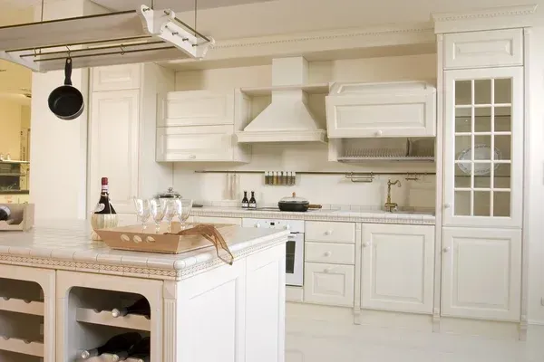 Bright white kitchen with cabinets, island, and glass-paneled door in a sunlit room