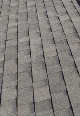 Close-up of gray roof shingles arranged in a staggered pattern.