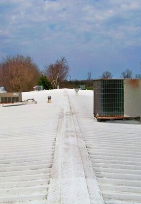 Snow-covered flat rooftop with HVAC units and vents under a cloudy sky