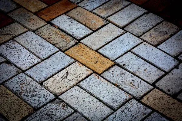 Diagonal brick pavement in gray, brown, and yellow tones, viewed from above