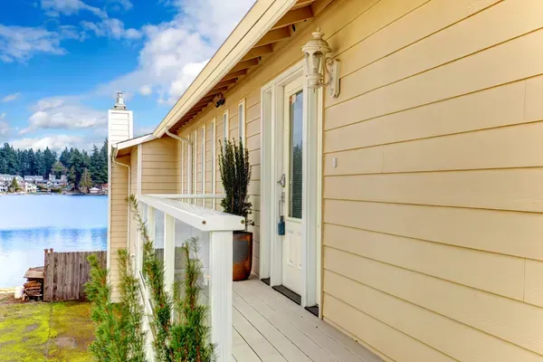 Cream-colored house porch overlooking a calm lake under a blue sky