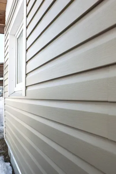 White vinyl house siding with a window on the left, shown from a close side angle.