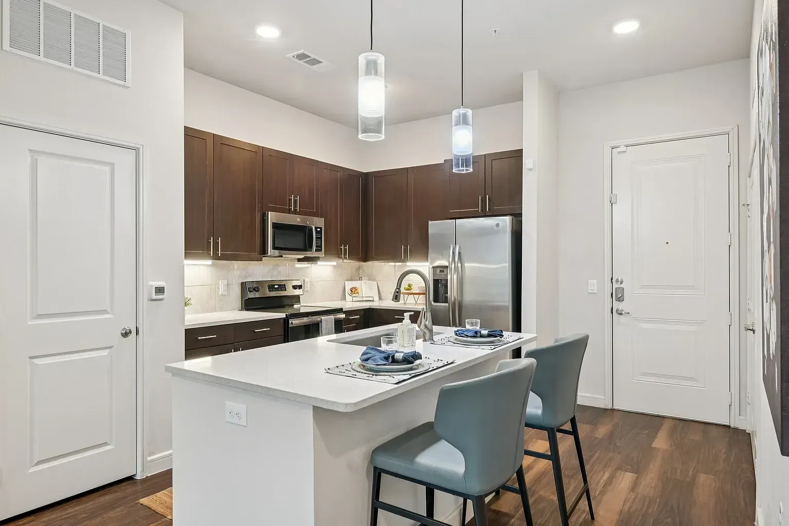 Modern kitchen with stainless steel appliances, dark wood cabinets, and a large island with bar stools.