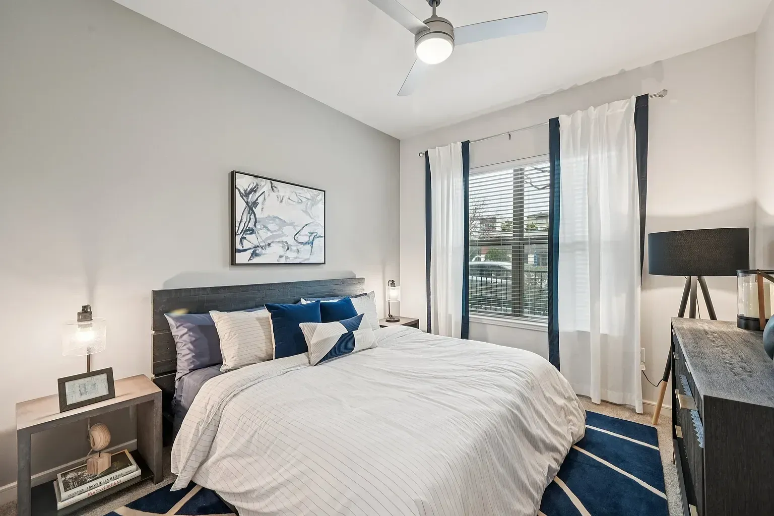 Modern bedroom with a king-size bed, ceiling fan, and abstract art.