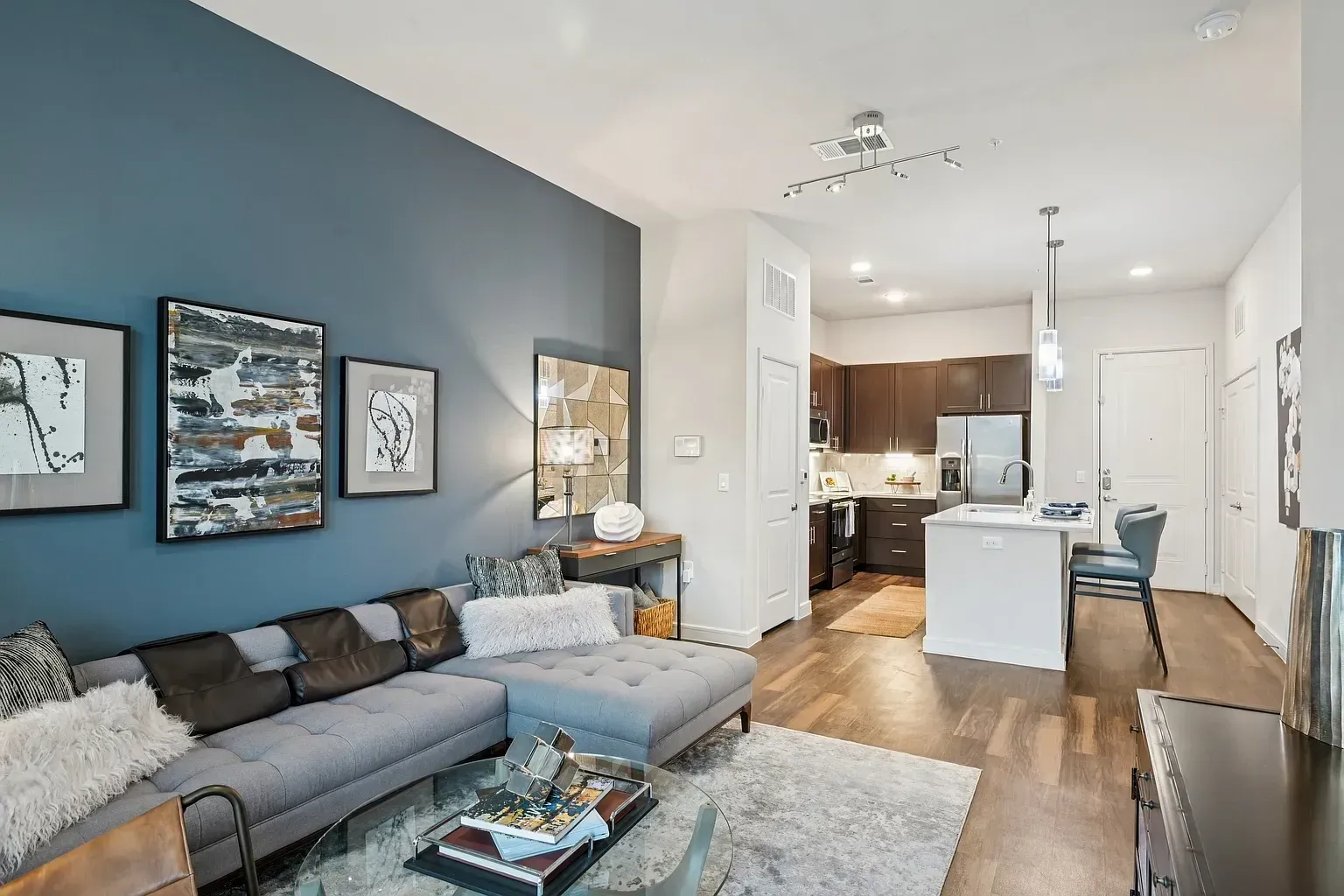 Modern living room and kitchen with sectional sofa, coffee table, and island.