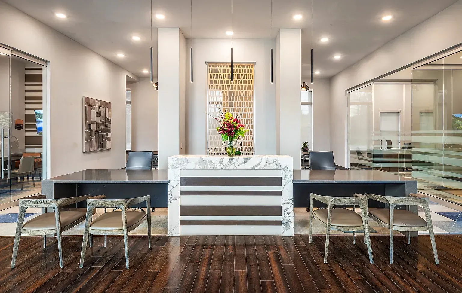 Modern reception desk with marble accents and stylish chairs in a well-lit lobby.