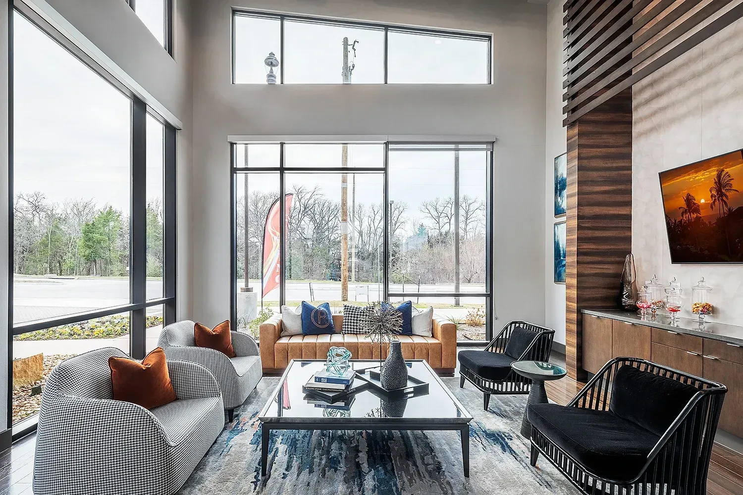 Stylish modern lounge area with large windows overlooking trees and a street.