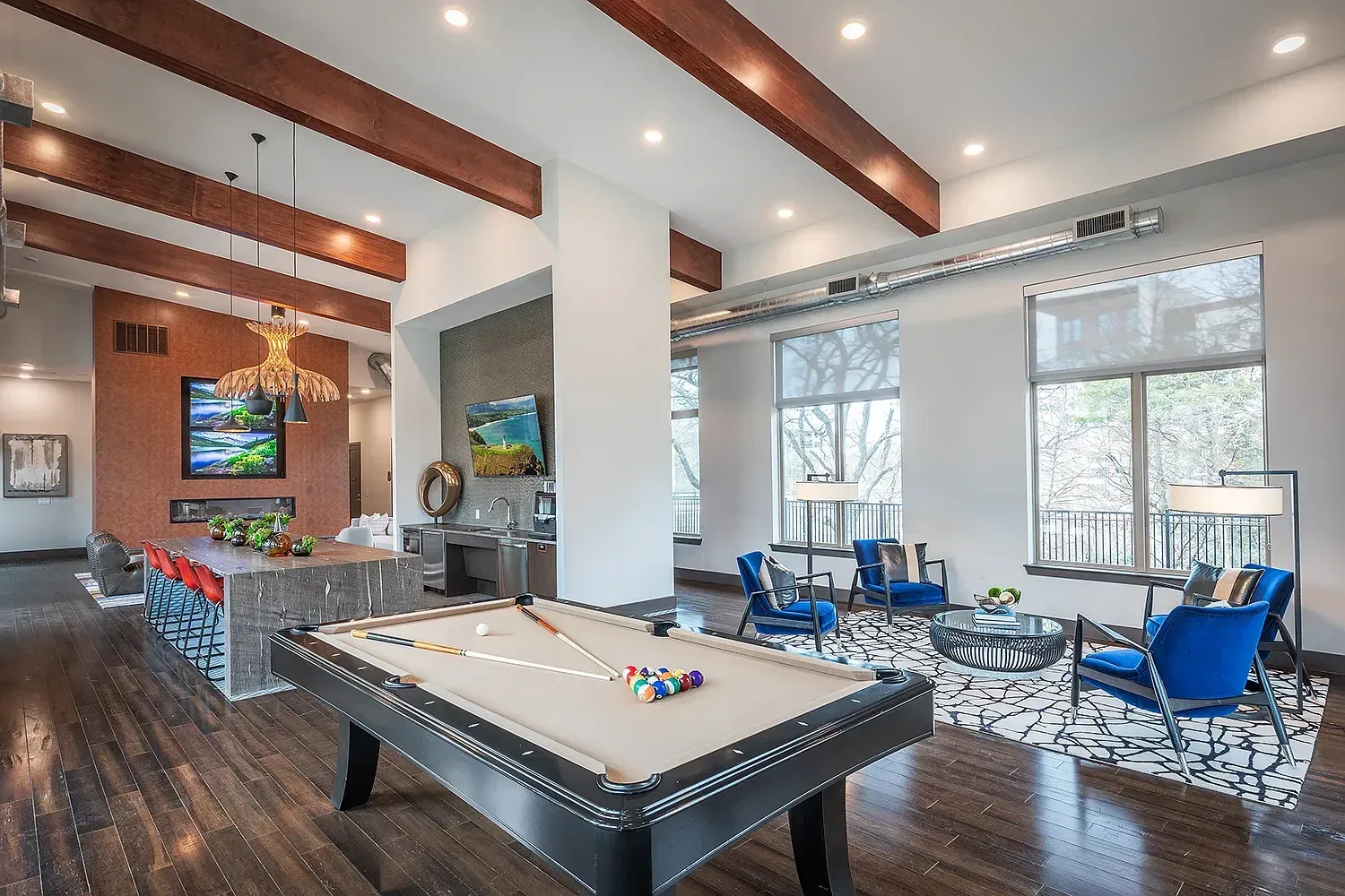 Pool table and lounge area with blue chairs in apartment community clubhouse.