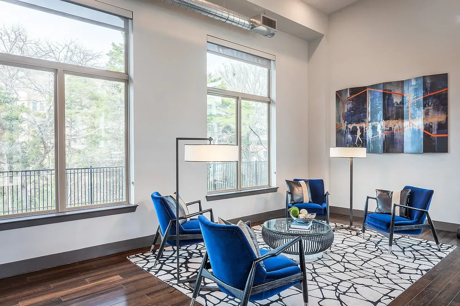 Modern living room with blue armchairs and a large abstract painting.