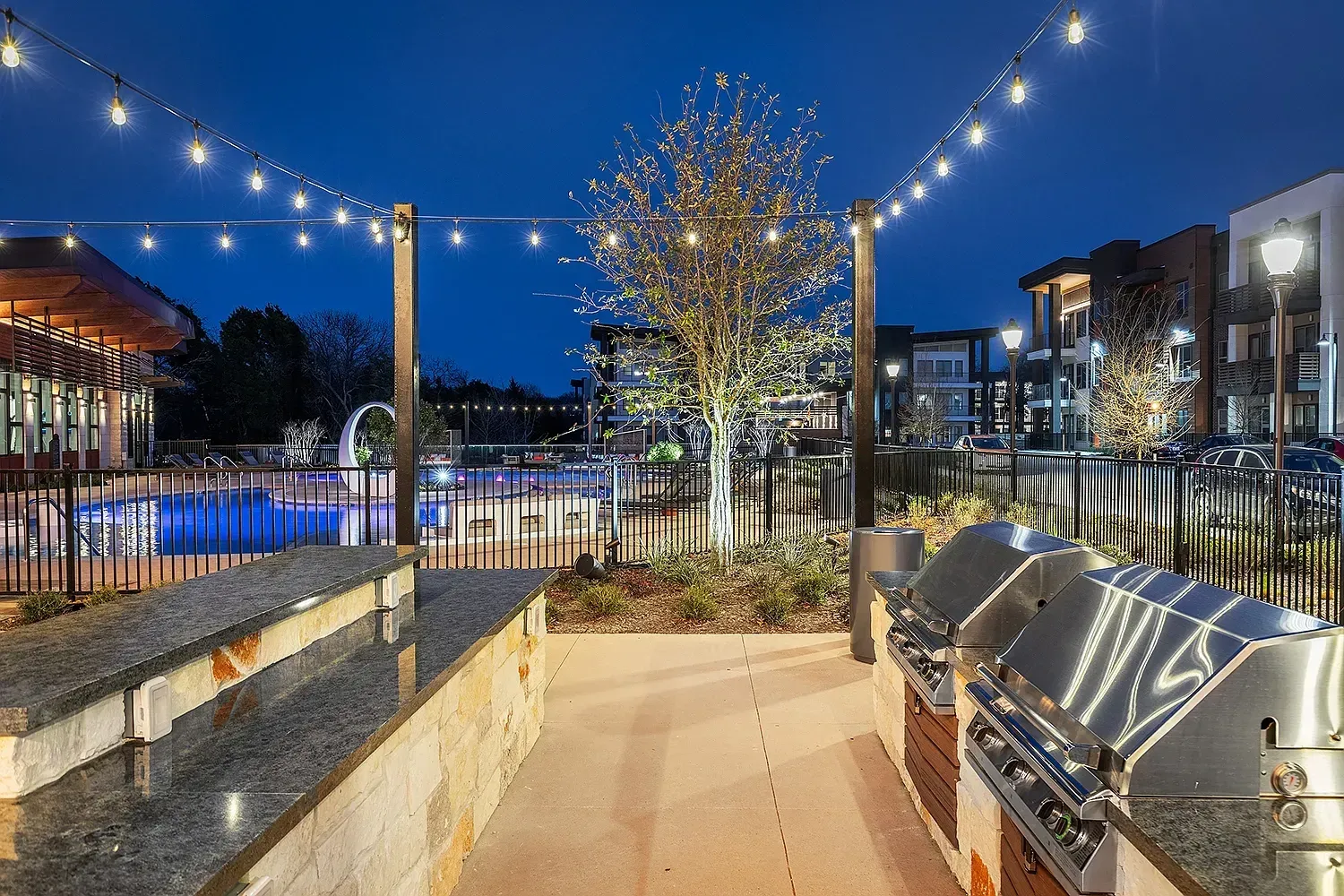 Outdoor grilling area and swimming pool at dusk.