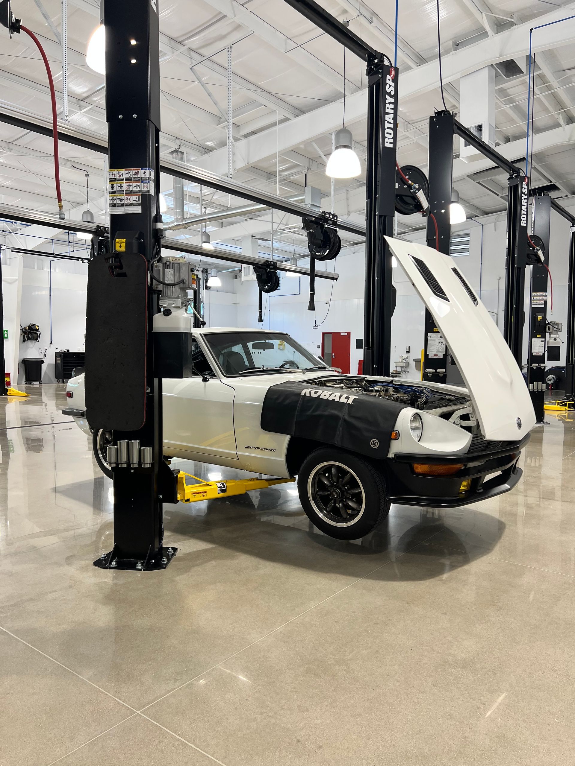 Classic car with hood open on a lift inside an auto repair shop | Reeder's Auto & Tire