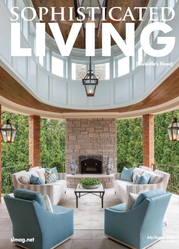 An open-air patio featuring a stone fireplace, light furniture with blue cushions, and a curved, white wooden ceiling.