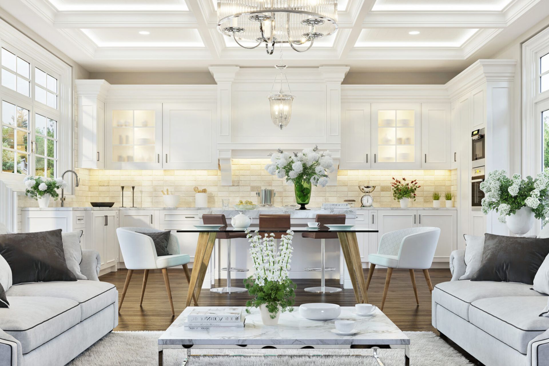 Modern open-concept kitchen and living area with white cabinetry, a glass dining table, and two grey sofas.