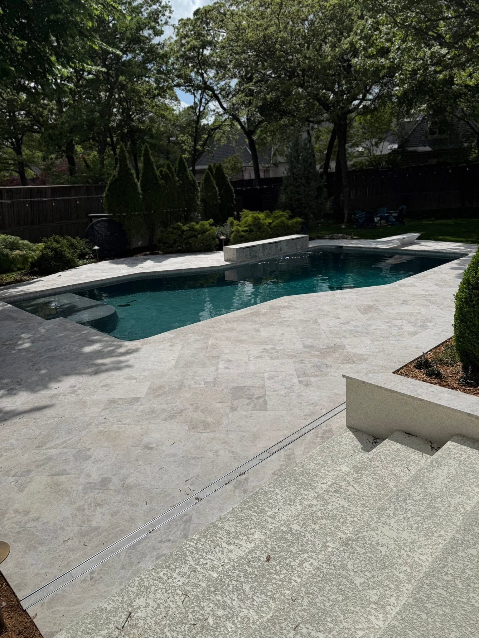 Backyard pool with stone patio, steps, and trees in shade