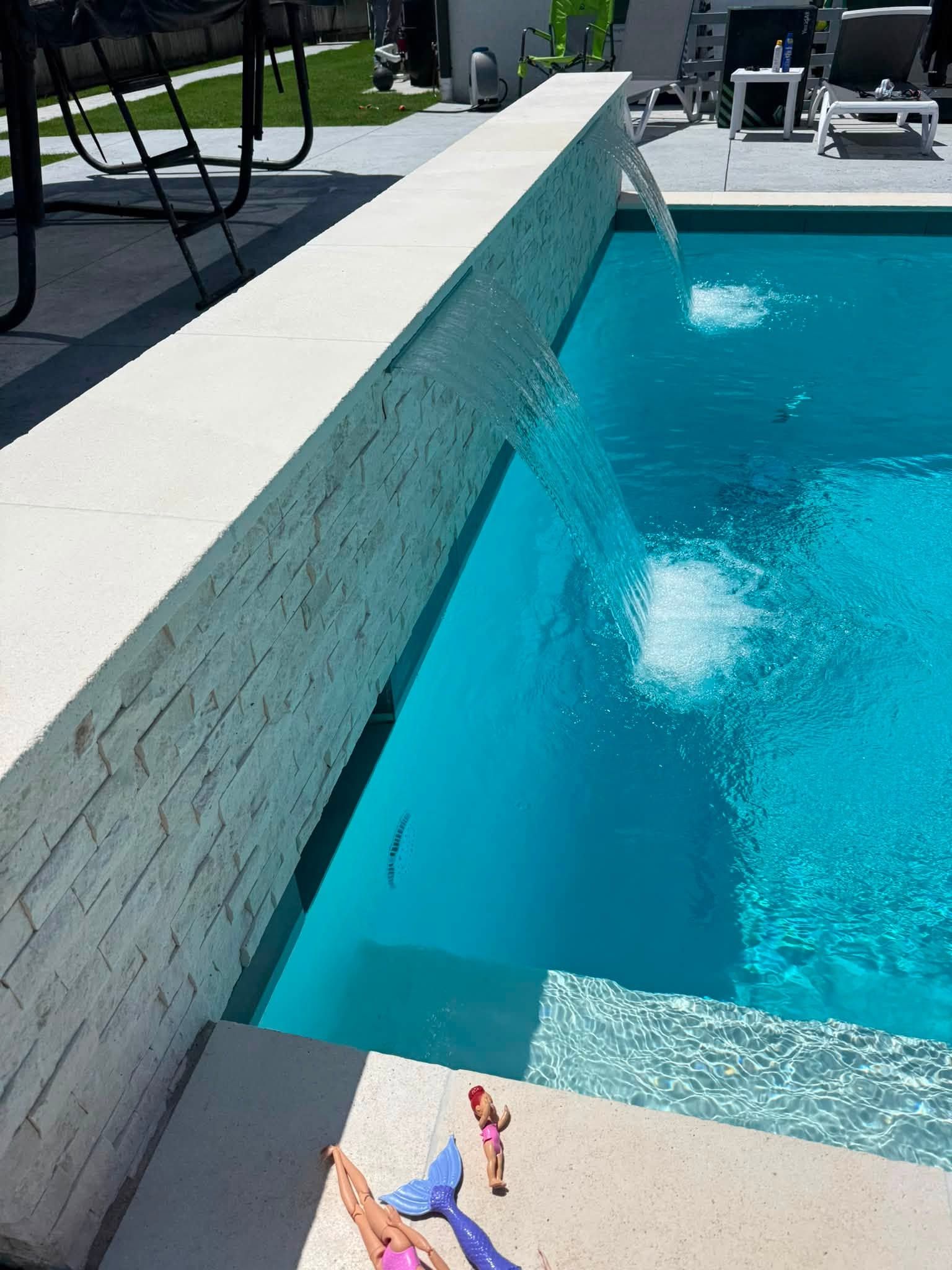 Swimming pool with a white wall, blue water, and a splash near the edge