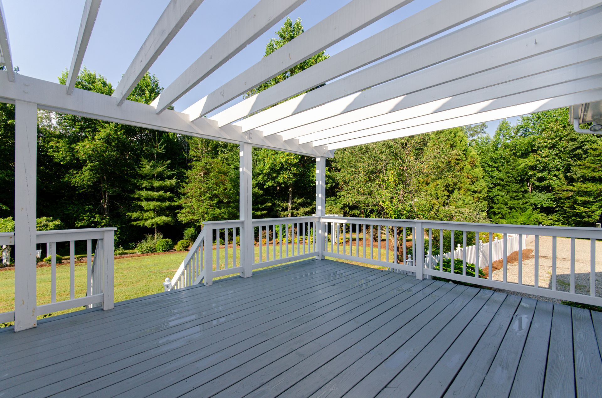 An empty deck with a white pergola over it