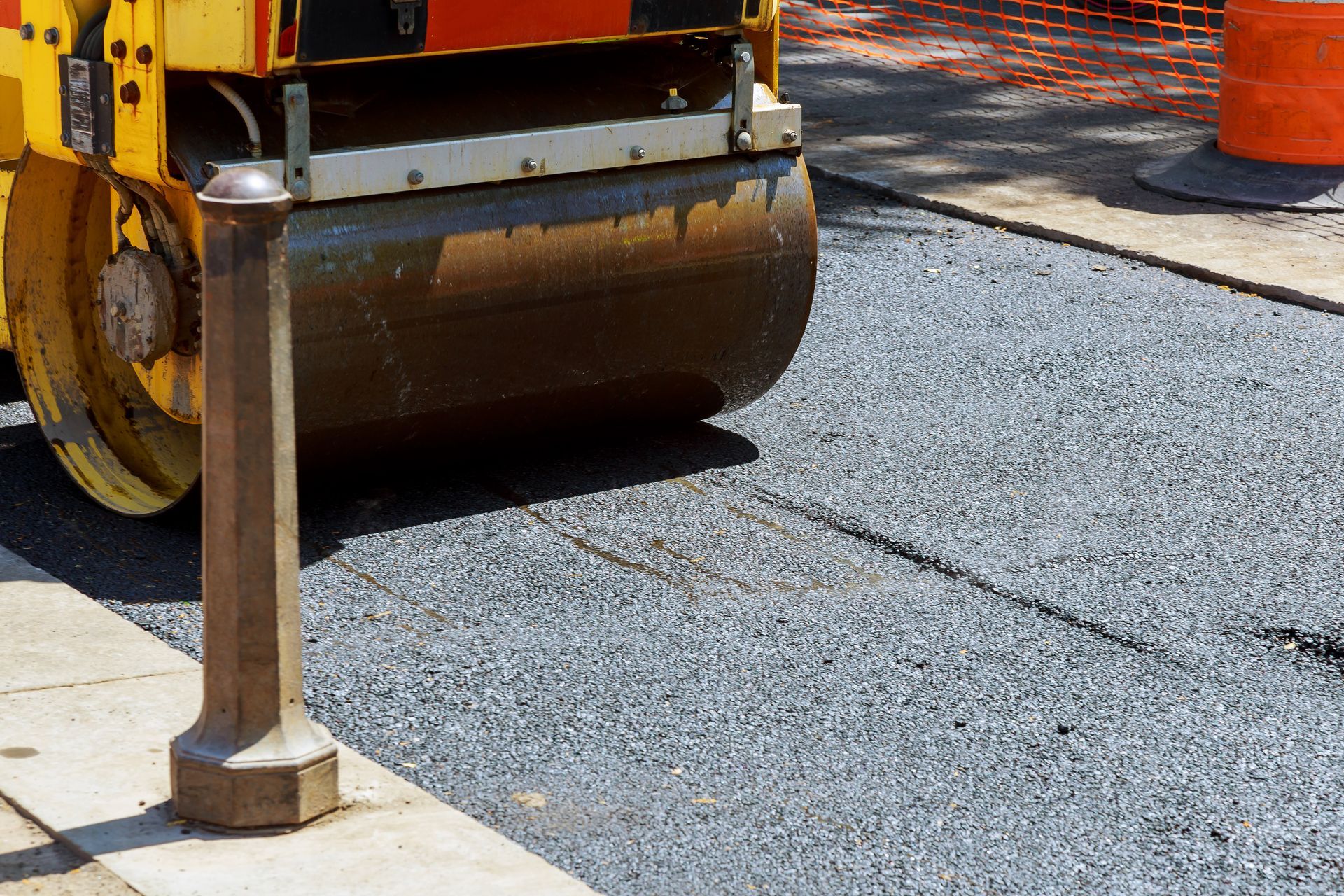 A roller is rolling asphalt on the side of a road.