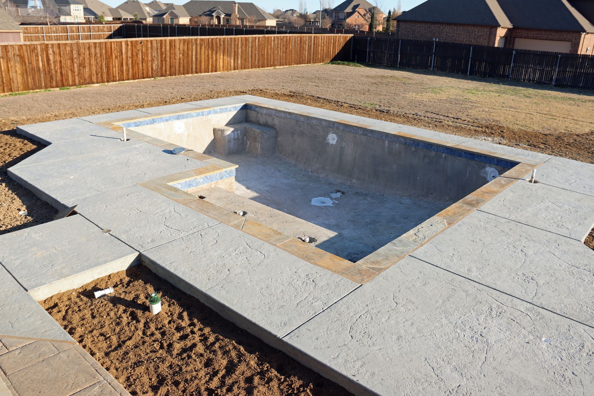 A swimming pool is being built in the backyard of a house