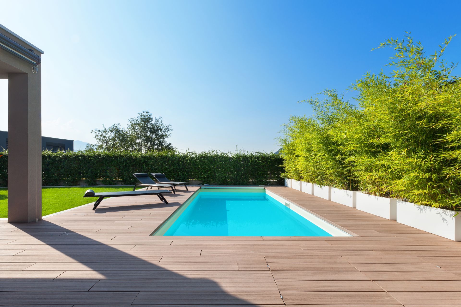 There is a large swimming pool in the backyard of a house.