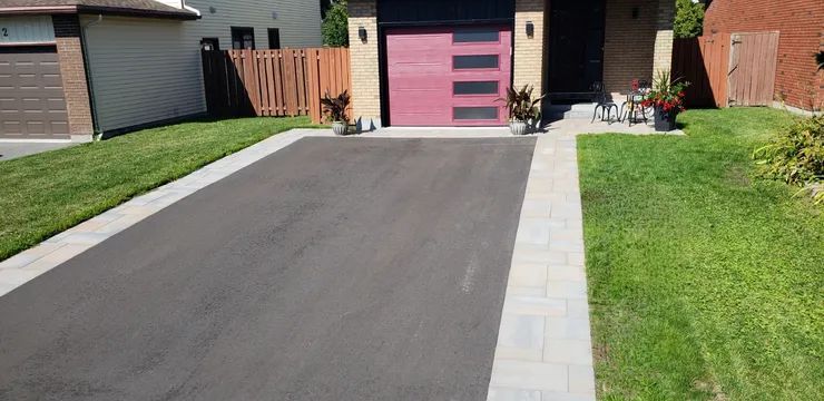 A driveway leading to a house with a pink garage door.