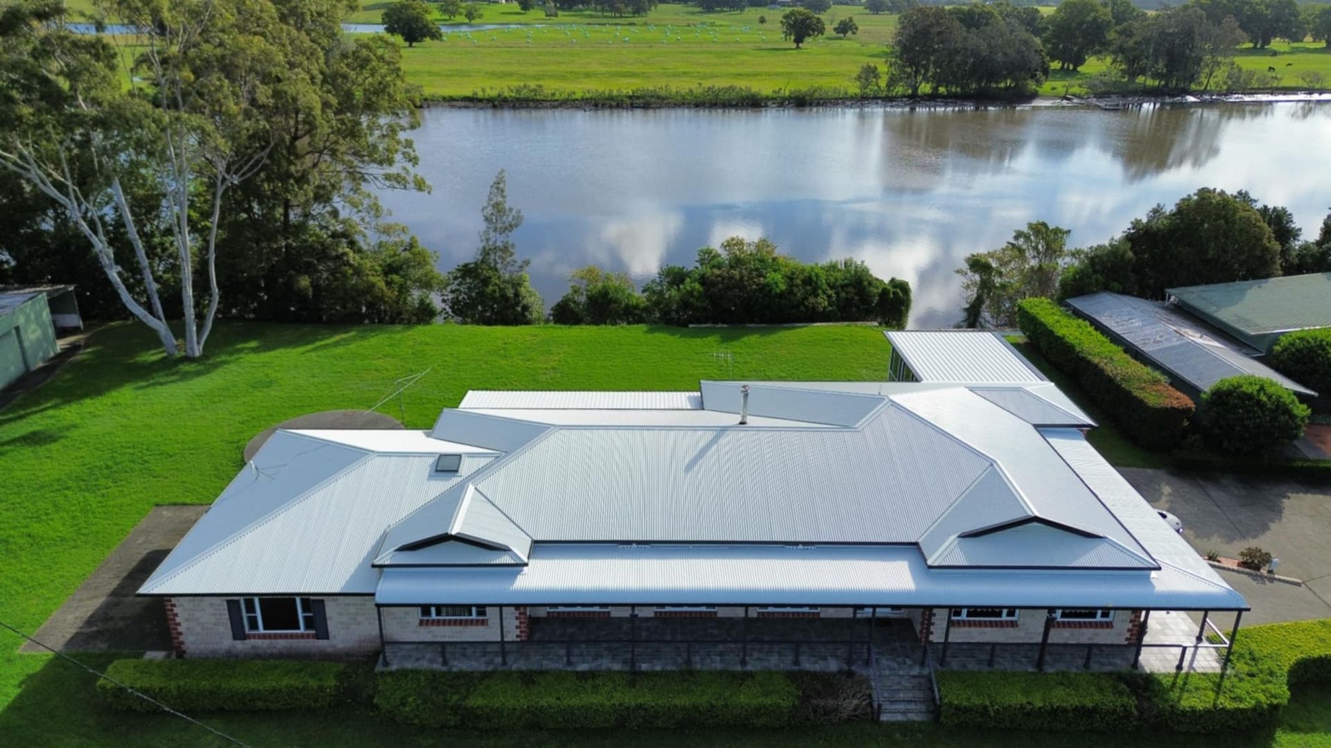 An Aerial View of a Large House in the Middle of a Lush Green Field — Tim Leach Metal Roofing in Wauchope, NSW