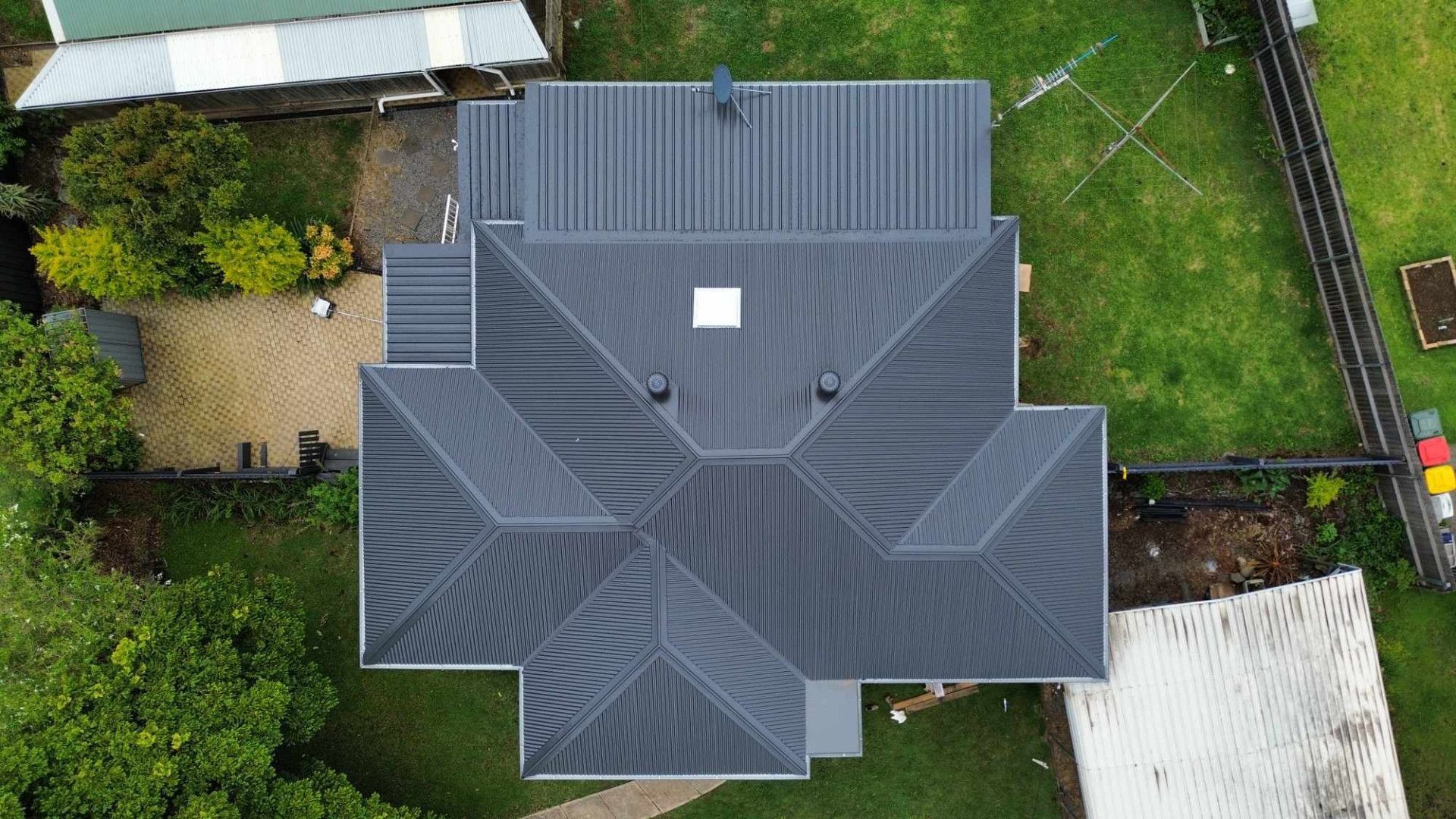 Overhead View of a House With a Dark Gray Roof Surrounded by Green Grass and Trees — Tim Leach Metal Roofing in Wauchope, NSW