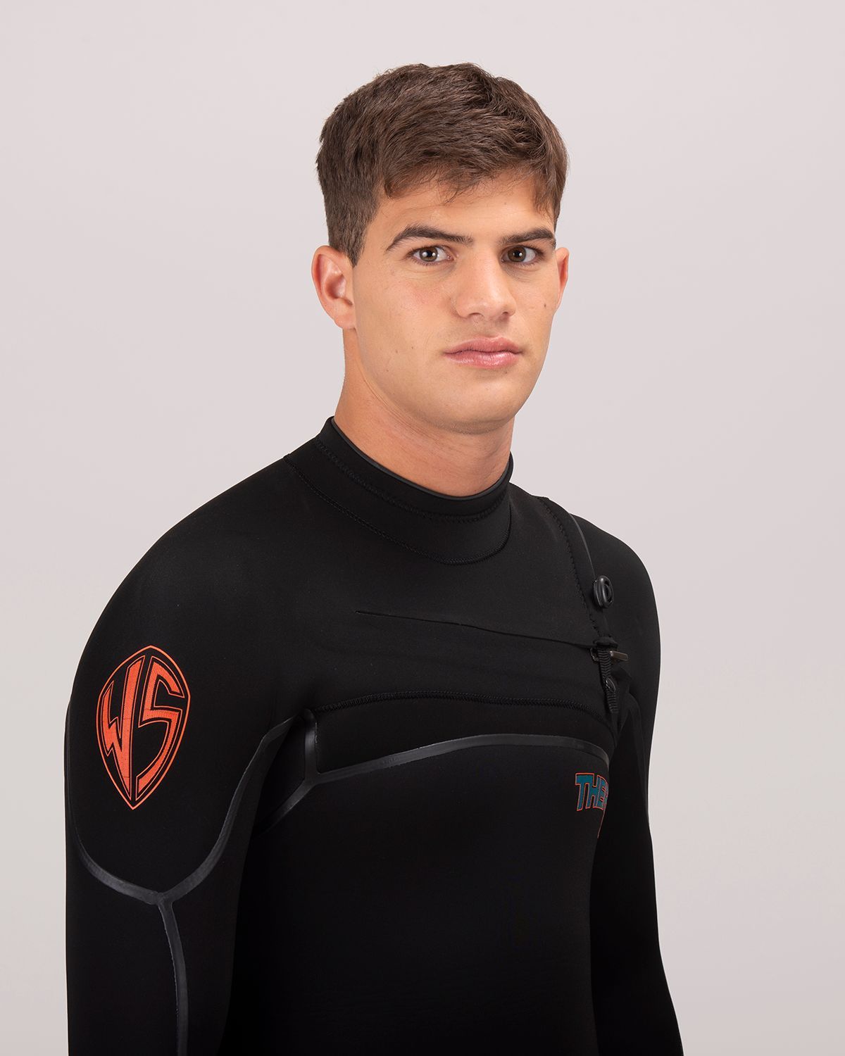 Hombre con traje de neopreno negro, con un traje de neopreno con un logotipo rojo en el hombro, mirando hacia adelante.