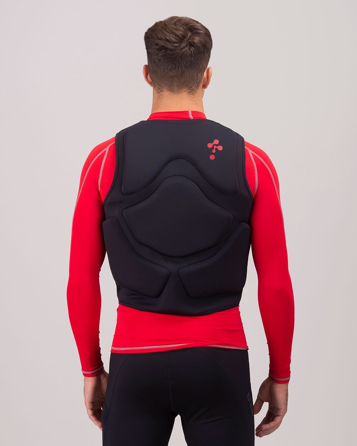 Hombre que lleva un chaleco antibalas negro para deportes acuáticos sobre una camisa roja de manga larga, vista trasera.