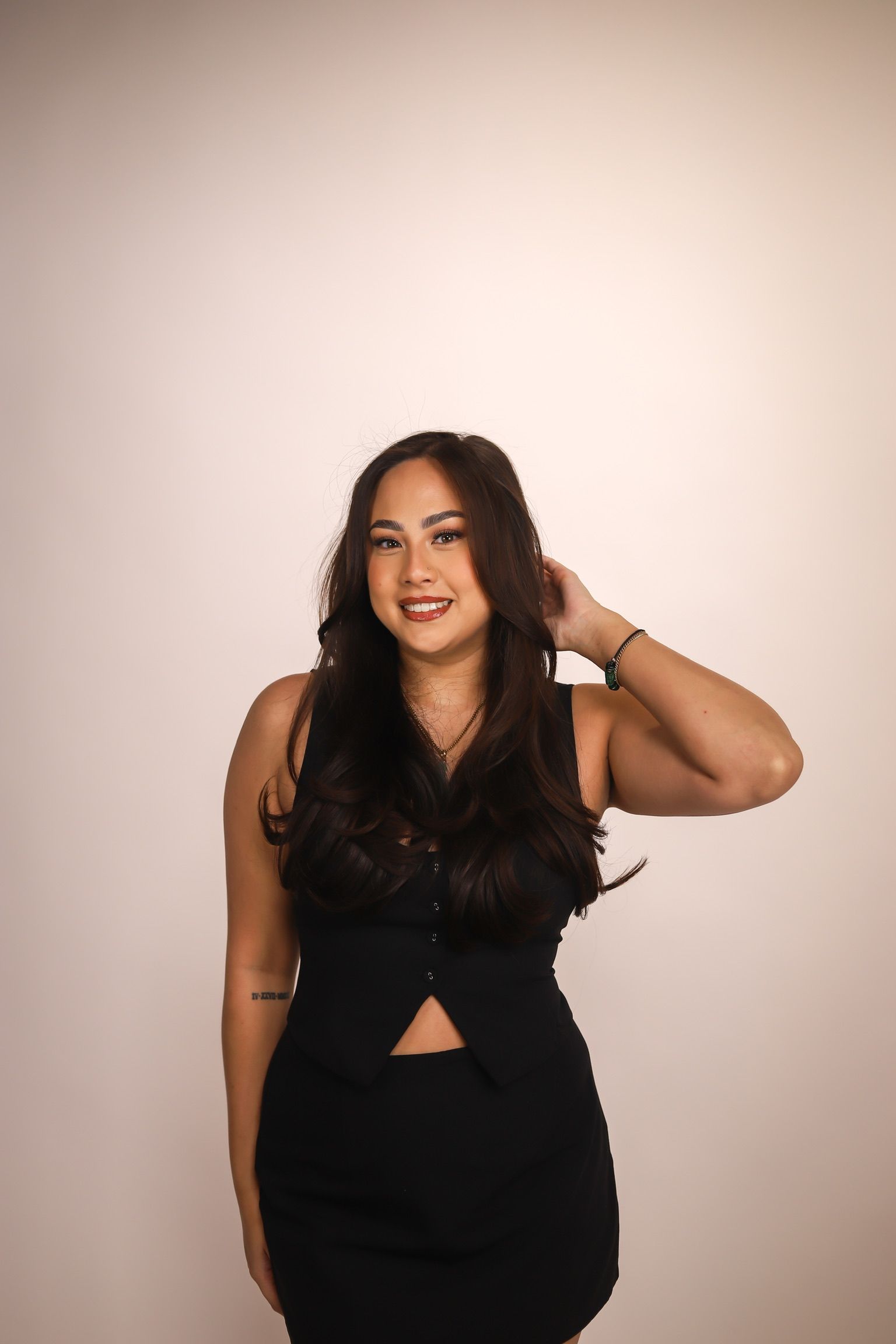 Woman in white underwear poses with arms raised against a beige backdrop.
