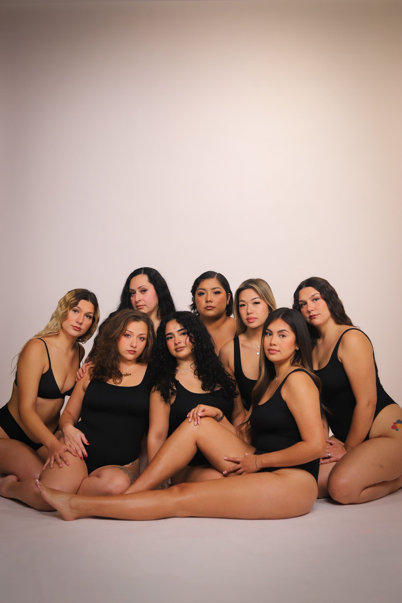Group of women in black lingerie, posing together. Light background, studio setting.